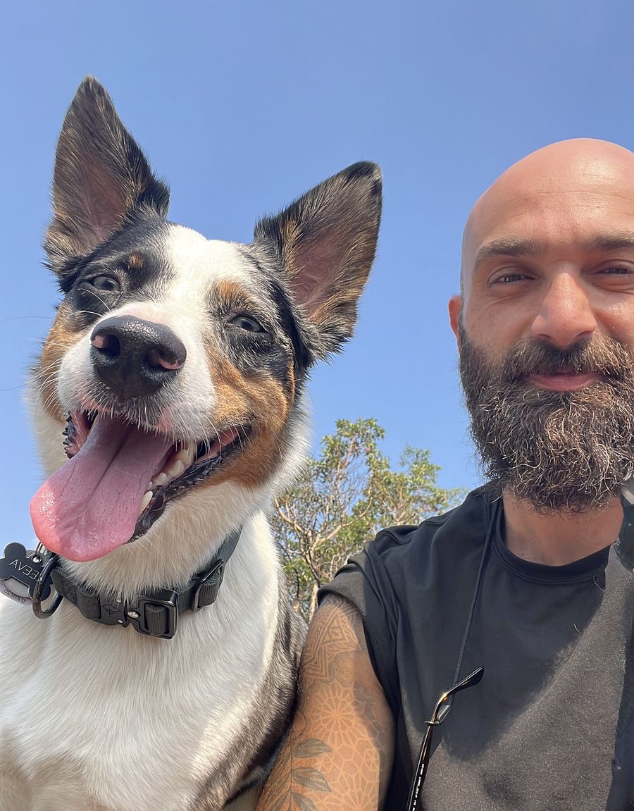 Hosam outdoors with Zeeva, a Heeler and Australian Shepherd mix